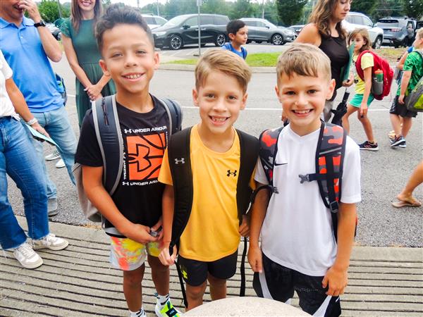 three boys smiling with backpacks